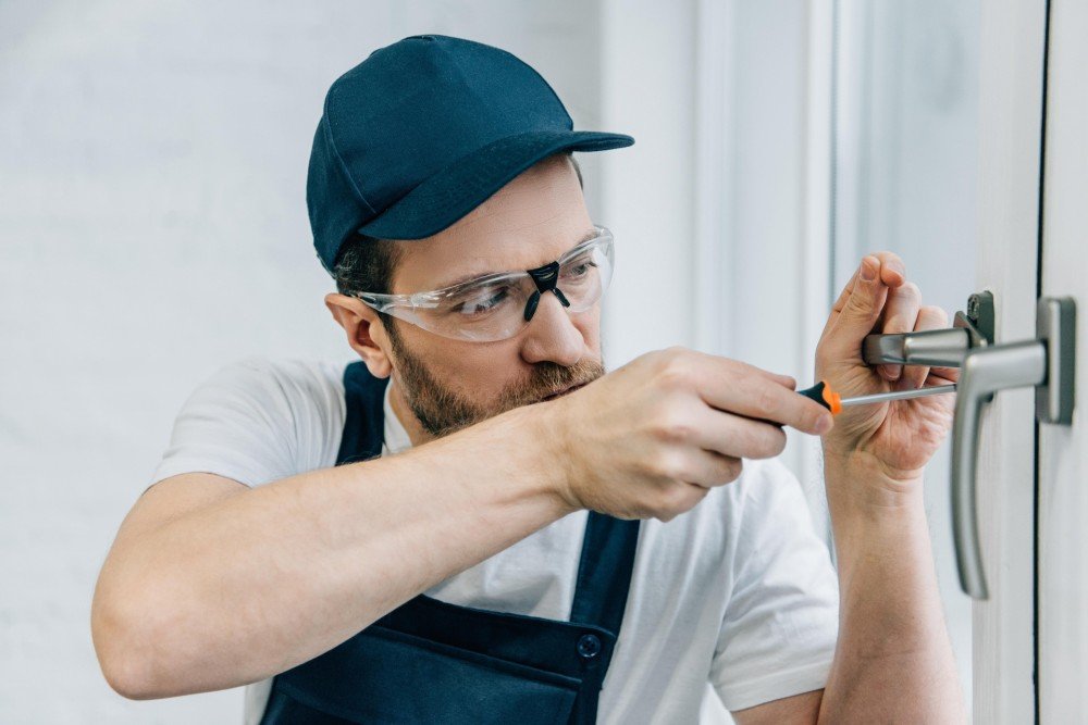 Technicien portant des lunettes de protection réglant la poignée d’une fenêtre